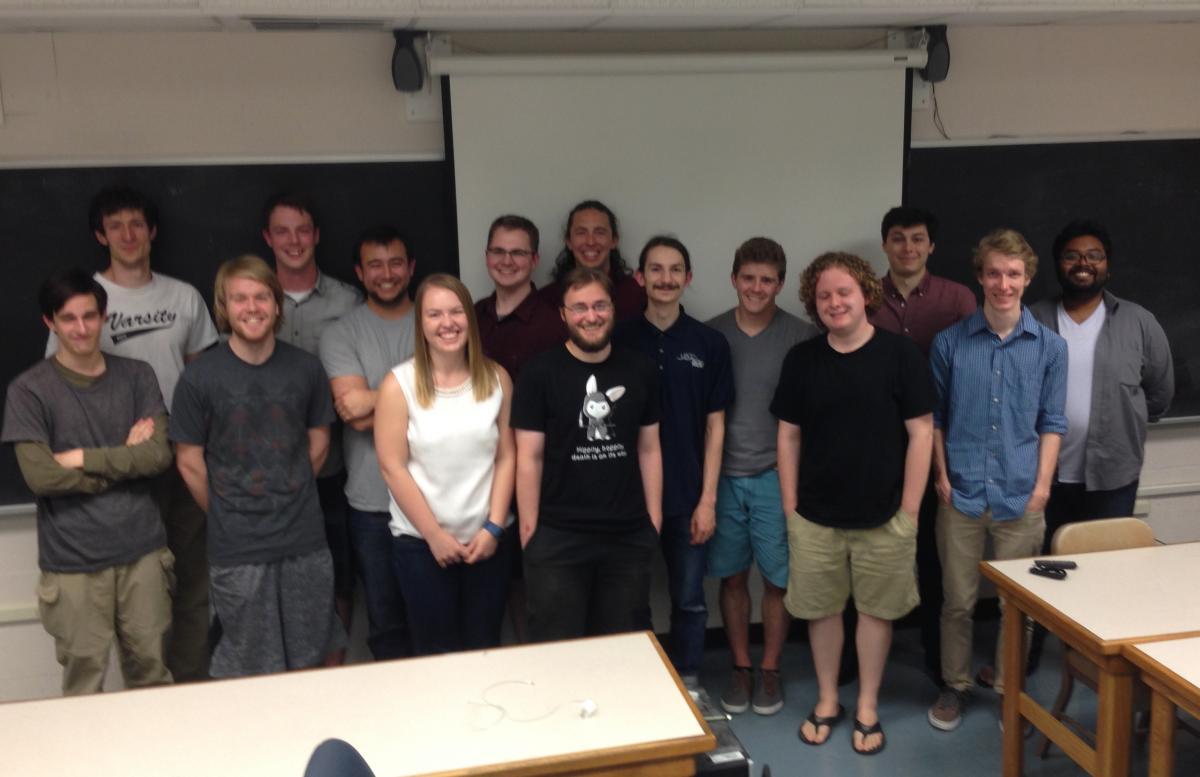 A group of 15 students posing together for a photo after completing their thesis presentations.