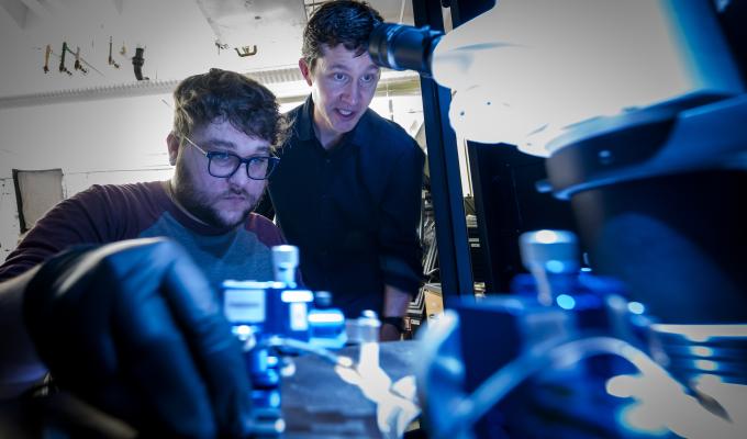 A professor shows a student how to use a piece of lab technology.